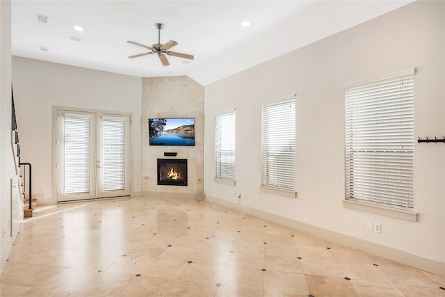 unfurnished living room with a tile fireplace, french doors, ceiling fan, and lofted ceiling