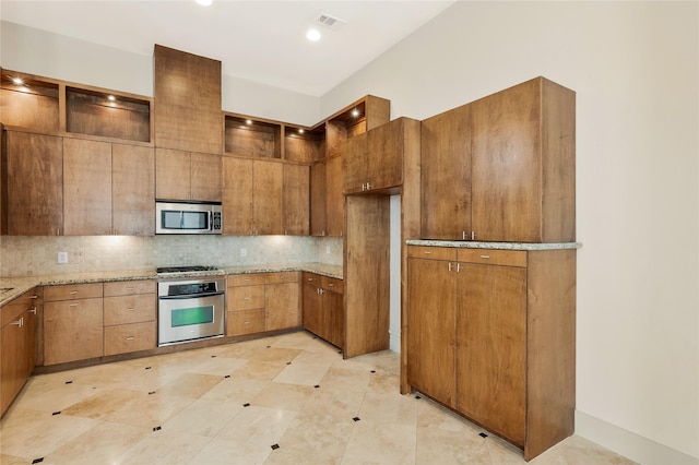 kitchen featuring backsplash, light stone countertops, and appliances with stainless steel finishes