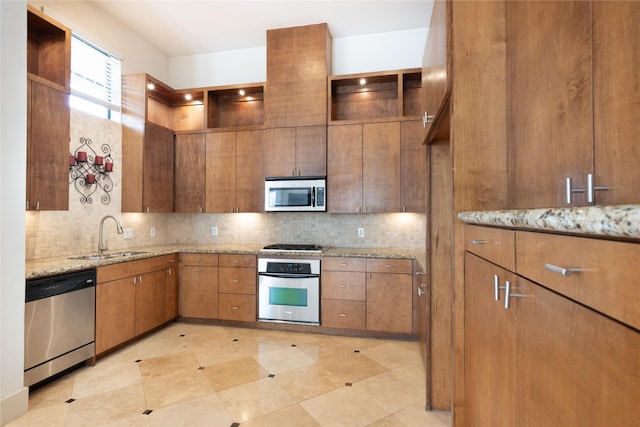 kitchen featuring backsplash, light stone countertops, sink, and appliances with stainless steel finishes