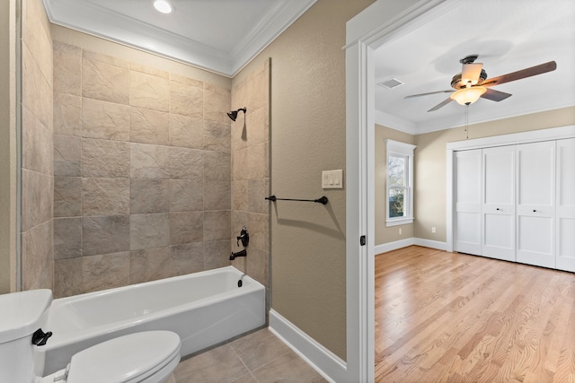 bathroom featuring ornamental molding, toilet, tiled shower / bath combo, and hardwood / wood-style floors