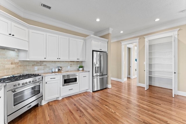 kitchen with range hood, stainless steel appliances, light stone countertops, white cabinets, and decorative backsplash