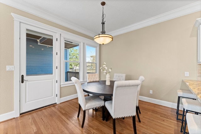 dining space with crown molding and light wood-type flooring