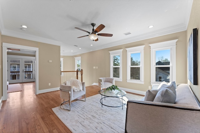 living room with crown molding, ceiling fan, light wood-type flooring, and french doors