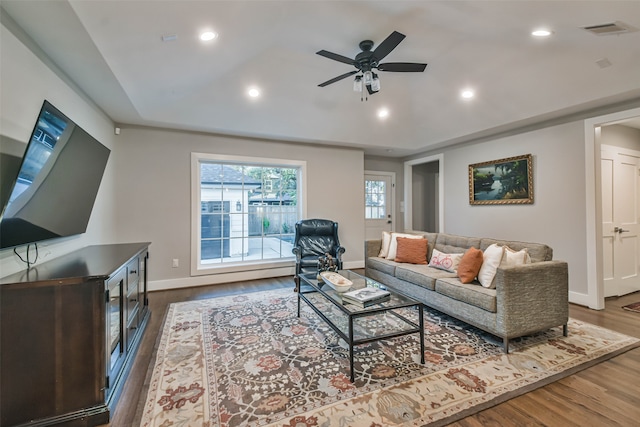 living room featuring a raised ceiling, dark hardwood / wood-style floors, and ceiling fan