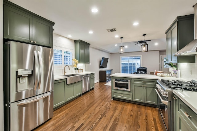 kitchen with sink, dark hardwood / wood-style flooring, decorative backsplash, green cabinets, and stainless steel appliances