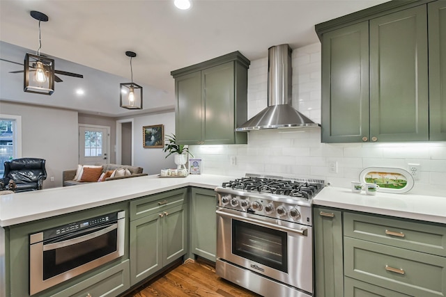 kitchen featuring wall chimney range hood, stainless steel range, backsplash, and green cabinetry