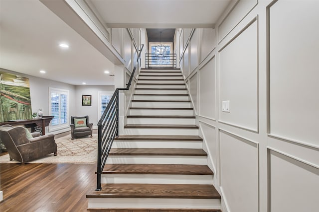 staircase featuring hardwood / wood-style floors and an inviting chandelier