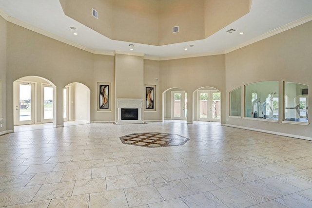 unfurnished living room with a wealth of natural light, ornamental molding, a high ceiling, and french doors