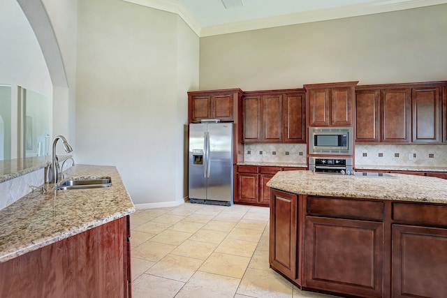 kitchen with sink, a center island, tasteful backsplash, light stone counters, and appliances with stainless steel finishes