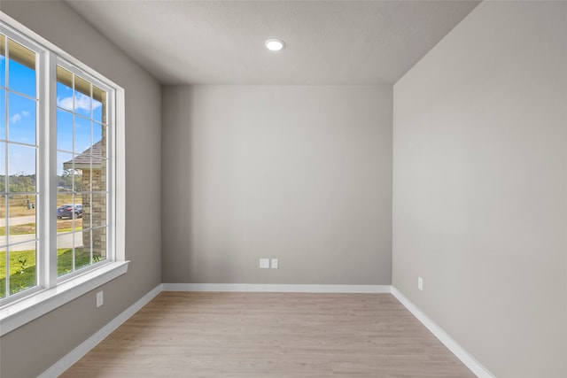 empty room with a textured ceiling and light hardwood / wood-style flooring