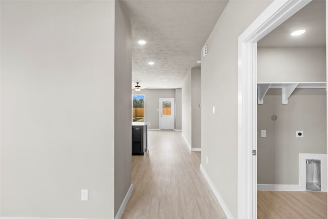 hallway with a textured ceiling and light wood-type flooring