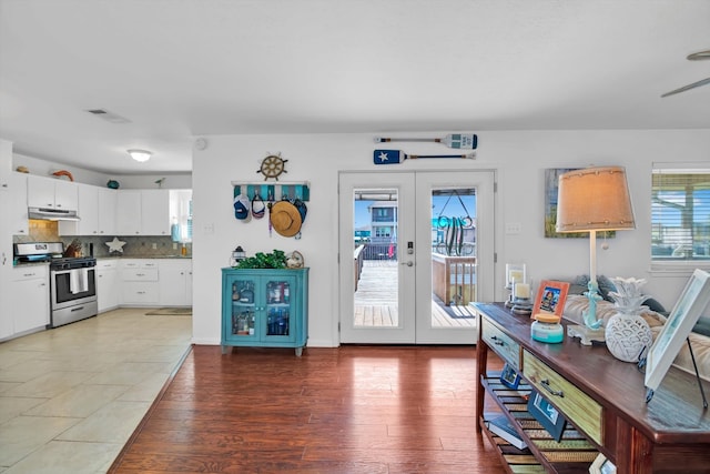 interior space featuring tasteful backsplash, french doors, dark hardwood / wood-style flooring, stainless steel stove, and white cabinets