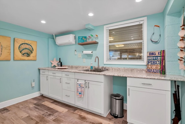 interior space featuring a wall mounted AC, sink, white cabinets, and light wood-type flooring