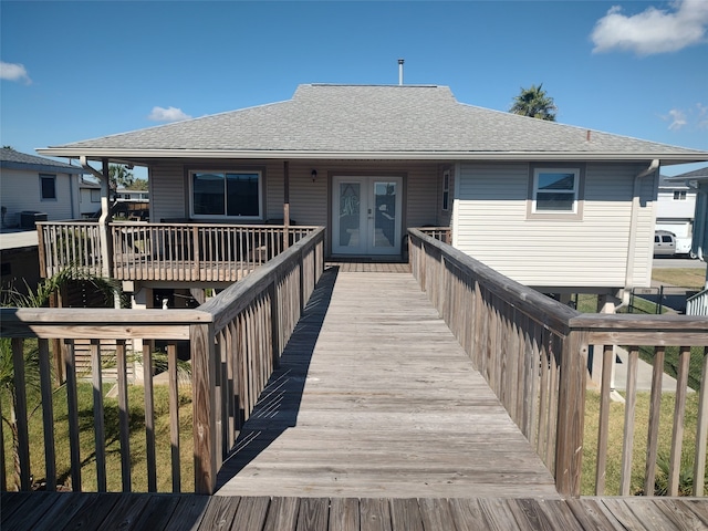 back of property featuring french doors, a deck, and a lawn