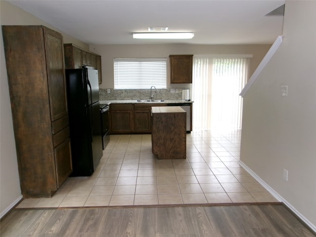 kitchen featuring backsplash, a kitchen island, sink, light hardwood / wood-style floors, and stainless steel appliances