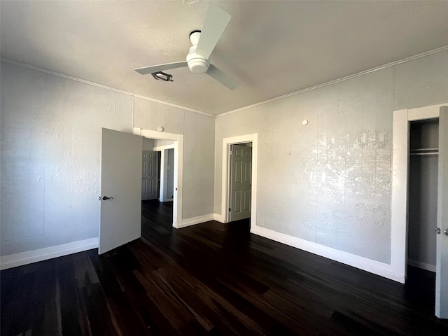 unfurnished bedroom featuring dark wood-type flooring, crown molding, a closet, and ceiling fan