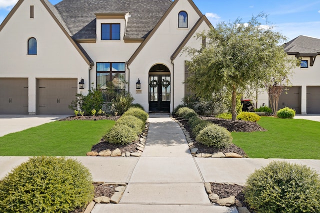 view of front of home featuring french doors, a front lawn, and a garage