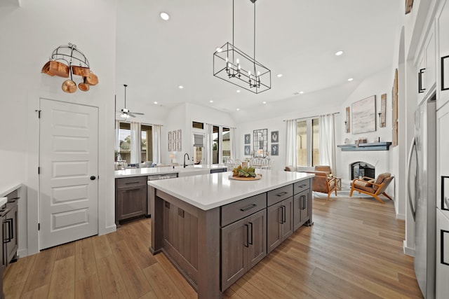 kitchen featuring ceiling fan with notable chandelier, a center island, light hardwood / wood-style floors, a high ceiling, and pendant lighting