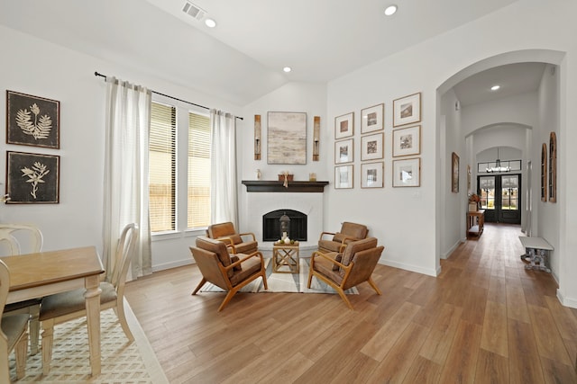 sitting room featuring vaulted ceiling, a fireplace, and light hardwood / wood-style floors