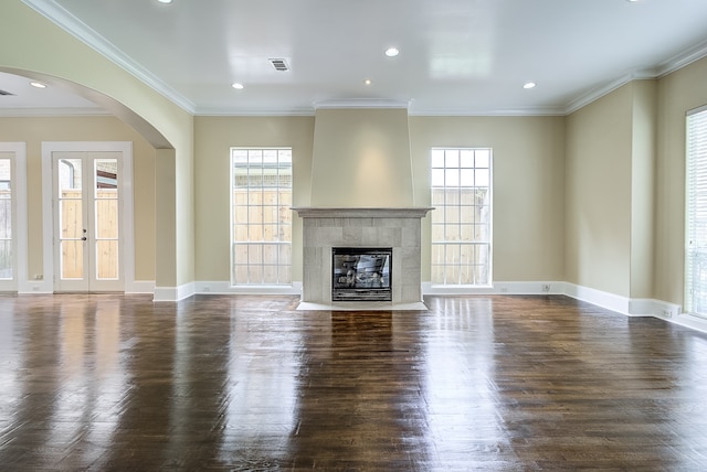 unfurnished living room featuring ornamental molding, dark wood-type flooring, and a tile fireplace