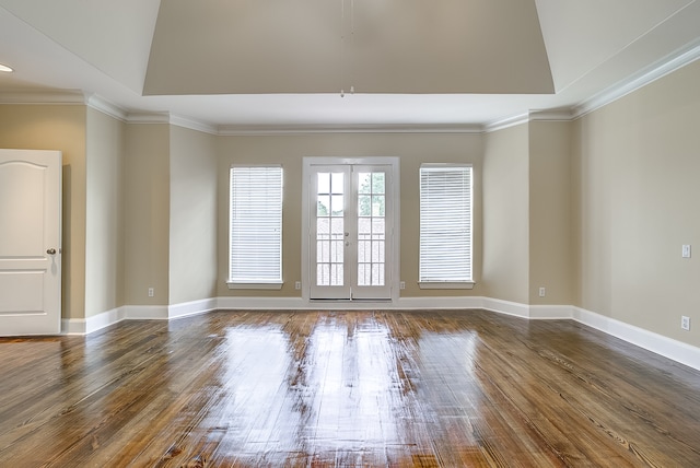 empty room featuring dark wood-type flooring, vaulted ceiling, crown molding, and french doors