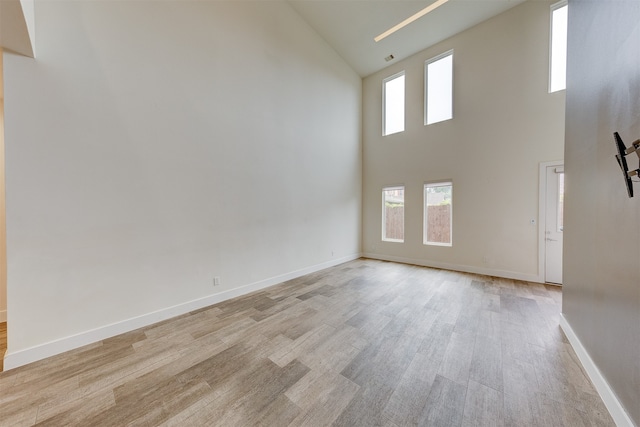 unfurnished living room featuring light hardwood / wood-style flooring and a towering ceiling