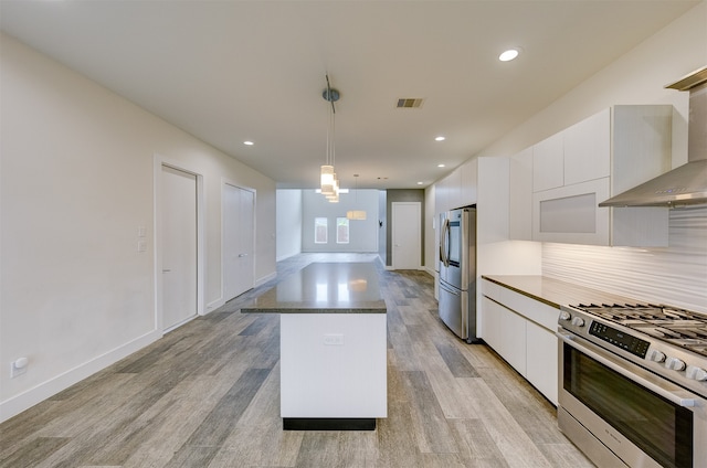 kitchen featuring white cabinetry, light hardwood / wood-style floors, stainless steel appliances, and hanging light fixtures