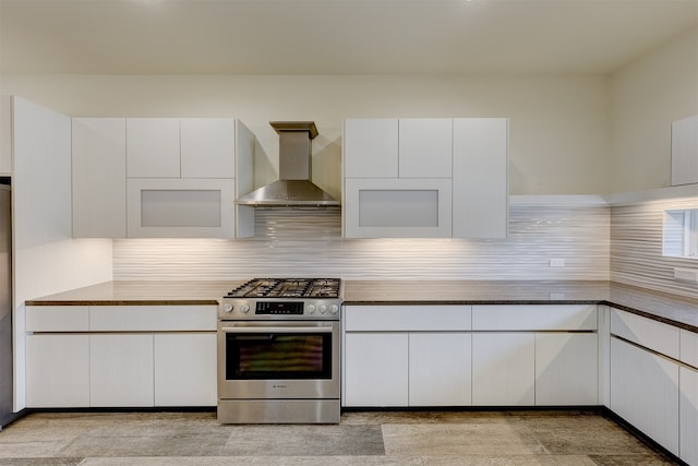 kitchen with wall chimney exhaust hood, white cabinets, high end stainless steel range oven, and tasteful backsplash