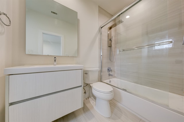 full bathroom featuring vanity, shower / bath combination with glass door, toilet, and tile patterned floors