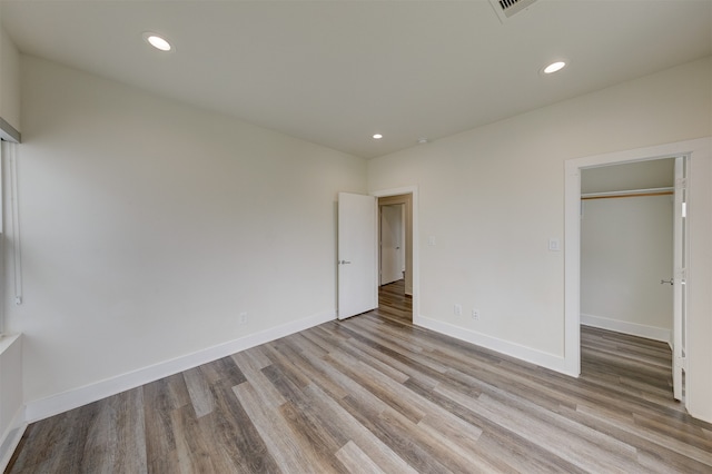 unfurnished bedroom featuring a closet, a walk in closet, and light wood-type flooring