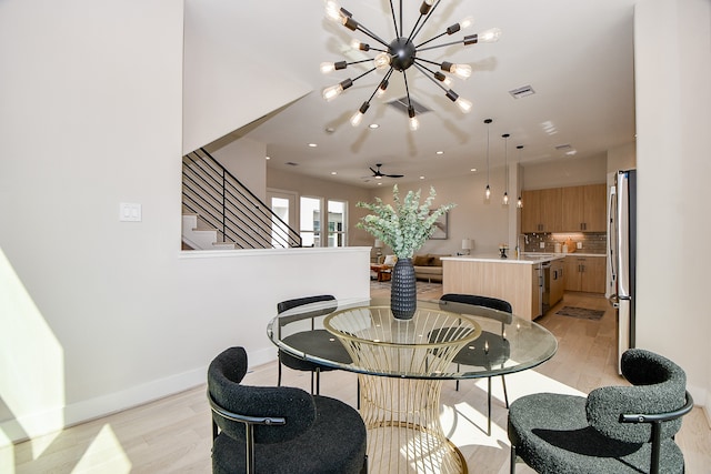 dining space featuring a notable chandelier, sink, and light wood-type flooring