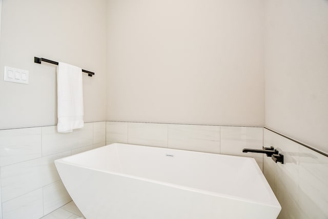 bathroom with a tub to relax in, tile walls, and tile patterned flooring