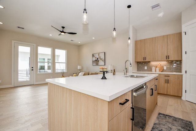 kitchen with light hardwood / wood-style floors, stainless steel dishwasher, an island with sink, and light brown cabinets