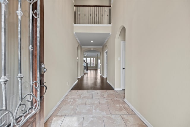 foyer entrance with a towering ceiling, crown molding, and light wood-type flooring