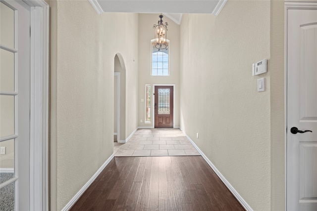 entrance foyer featuring a chandelier, crown molding, and light wood-type flooring