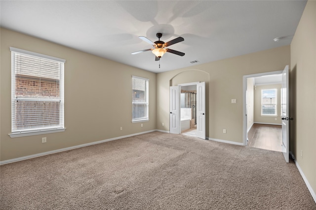 unfurnished bedroom featuring ceiling fan, light carpet, and ensuite bath