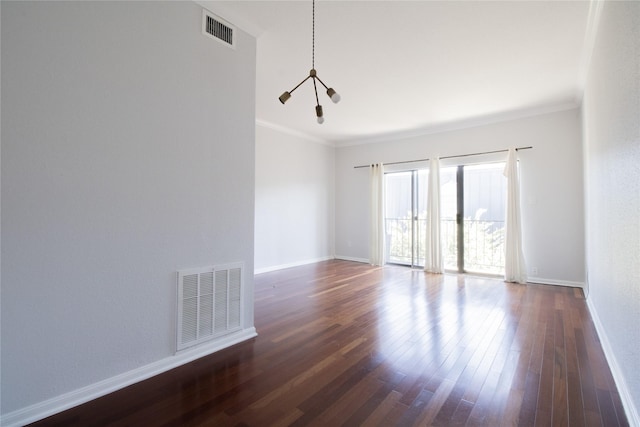 spare room featuring ornamental molding, dark hardwood / wood-style flooring, and a notable chandelier