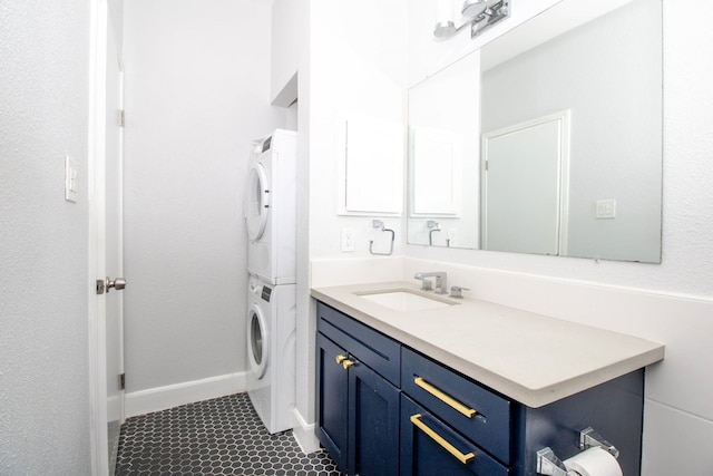 bathroom with baseboards, vanity, and stacked washer and dryer