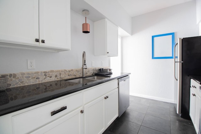 kitchen featuring dark tile patterned floors, appliances with stainless steel finishes, white cabinetry, and a sink