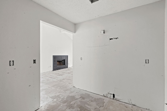 empty room with a textured ceiling and a tiled fireplace