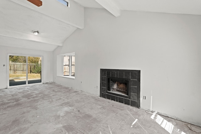 unfurnished living room with ceiling fan, high vaulted ceiling, beamed ceiling, and a tile fireplace