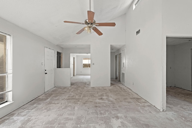 unfurnished living room featuring a wealth of natural light, a textured ceiling, high vaulted ceiling, and ceiling fan