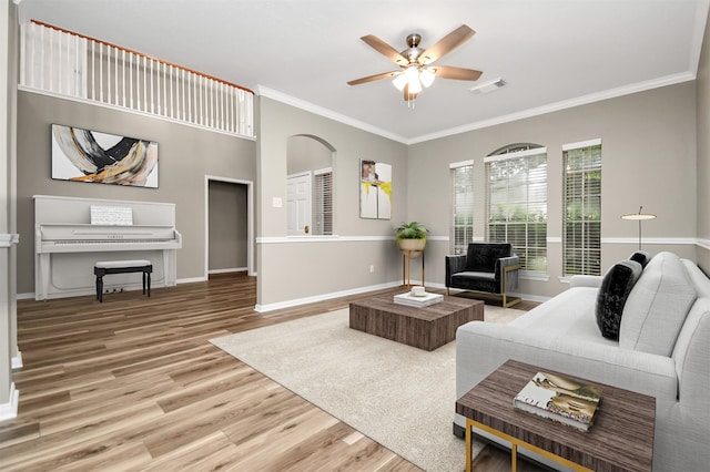 living room with wood-type flooring, ceiling fan, and crown molding