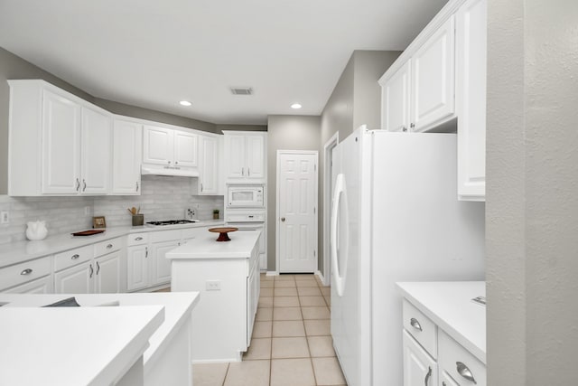 kitchen with white cabinets, decorative backsplash, white appliances, and a kitchen island