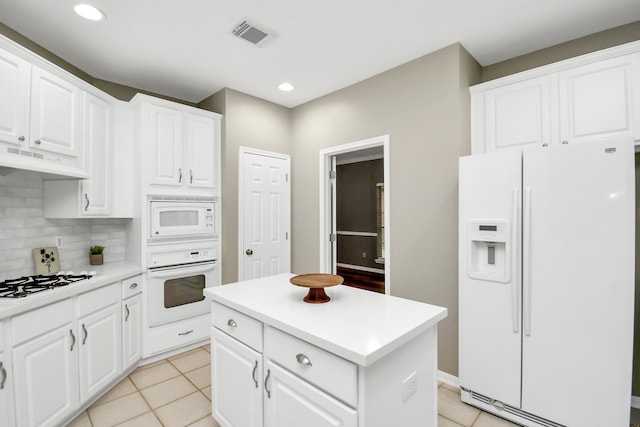 kitchen featuring white cabinetry, light tile patterned floors, white appliances, a center island, and decorative backsplash