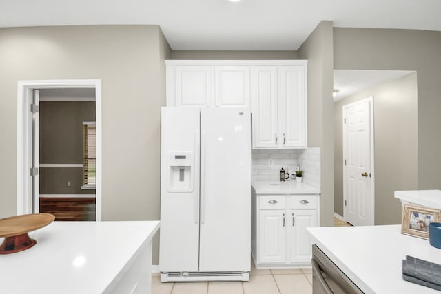 kitchen with white fridge with ice dispenser, backsplash, light tile patterned floors, and white cabinets