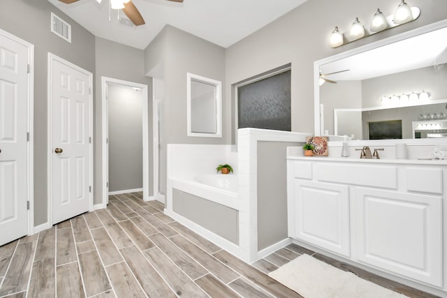 bathroom with hardwood / wood-style floors, a tub, ceiling fan, and vanity