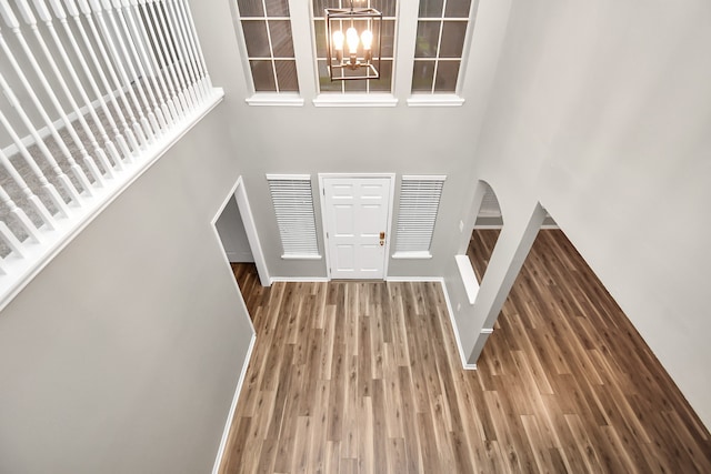 foyer featuring a towering ceiling, an inviting chandelier, and hardwood / wood-style flooring