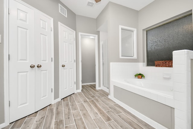 bathroom with hardwood / wood-style flooring and separate shower and tub