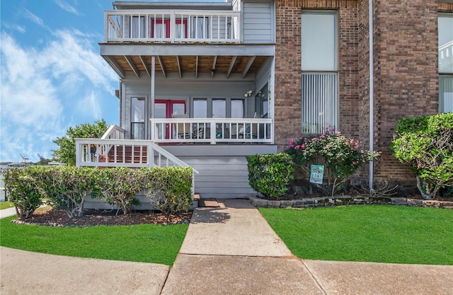 view of front of house featuring a balcony and a front yard